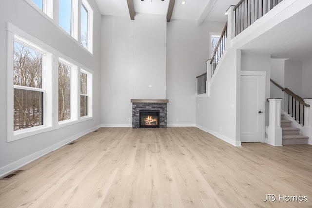 unfurnished living room with beam ceiling, visible vents, plenty of natural light, and baseboards