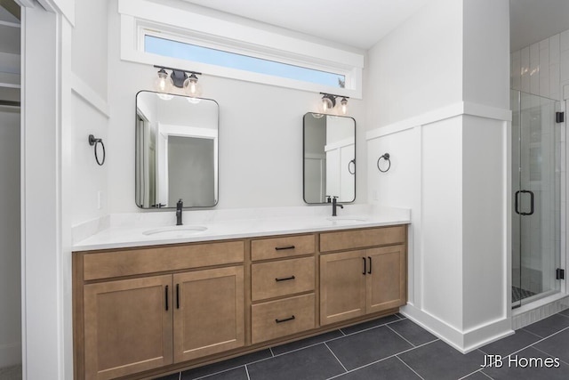 bathroom featuring double vanity, a shower stall, a sink, and tile patterned floors