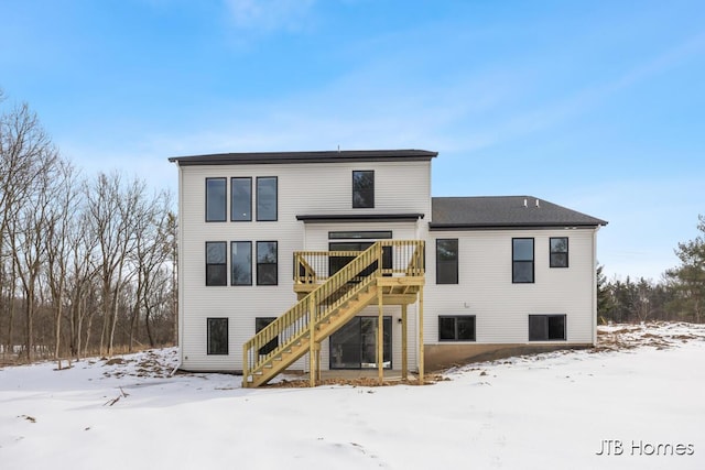 snow covered house with a wooden deck and stairs