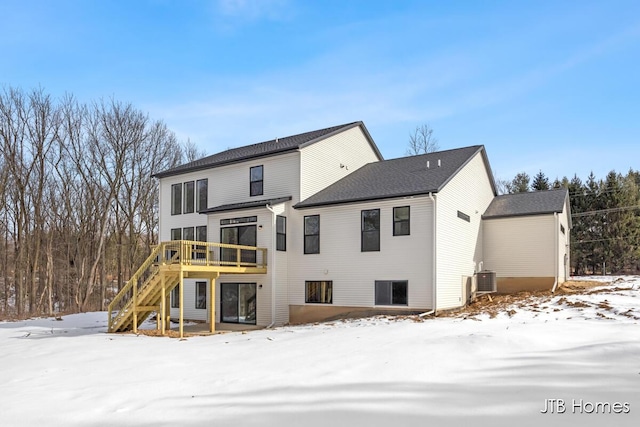 snow covered back of property featuring stairs, central AC, and a deck