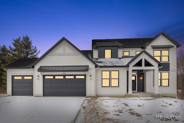 modern farmhouse with metal roof, an attached garage, a shingled roof, driveway, and a standing seam roof