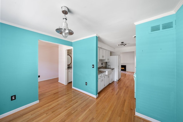 kitchen featuring white cabinets, sink, crown molding, and light hardwood / wood-style flooring