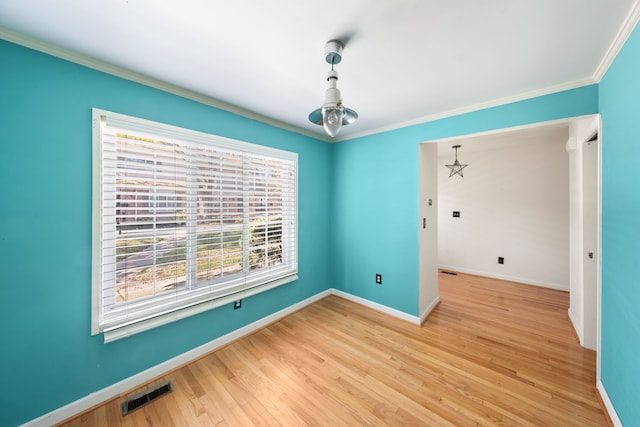 spare room featuring light wood-type flooring, an inviting chandelier, and crown molding