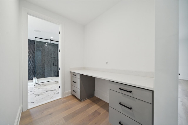 home office featuring light hardwood / wood-style floors and built in desk