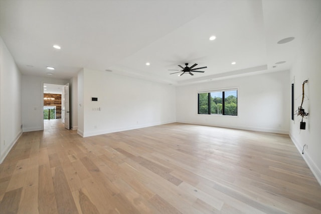 unfurnished room featuring a tray ceiling, light hardwood / wood-style flooring, and ceiling fan