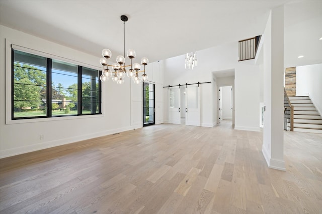 interior space featuring a barn door, light hardwood / wood-style floors, and a notable chandelier