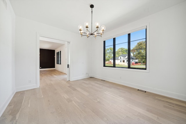 empty room with light hardwood / wood-style flooring and a chandelier