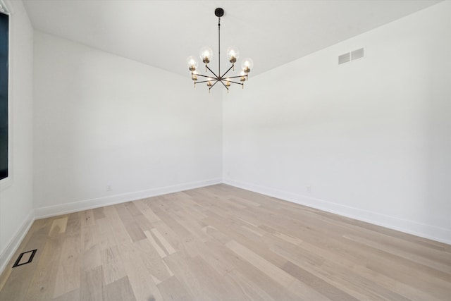 unfurnished room with a notable chandelier and light hardwood / wood-style floors