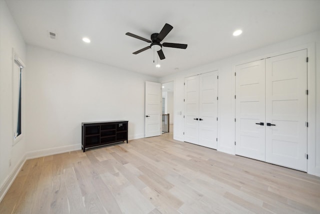 unfurnished bedroom with ceiling fan, multiple closets, and light hardwood / wood-style flooring