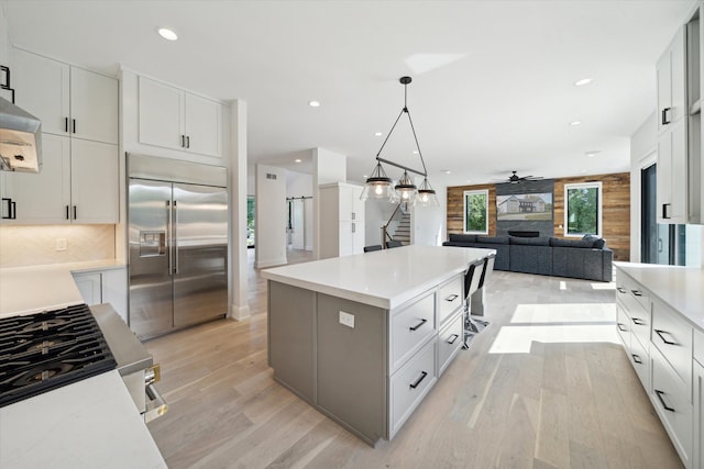 kitchen with white cabinetry, a center island, light hardwood / wood-style flooring, built in refrigerator, and pendant lighting