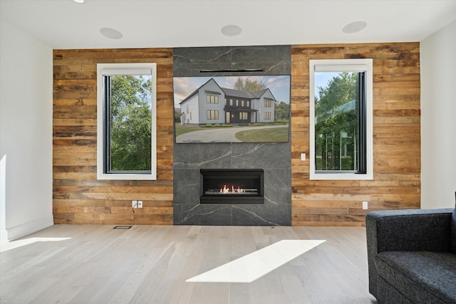 living room with a tile fireplace, hardwood / wood-style floors, a healthy amount of sunlight, and wood walls