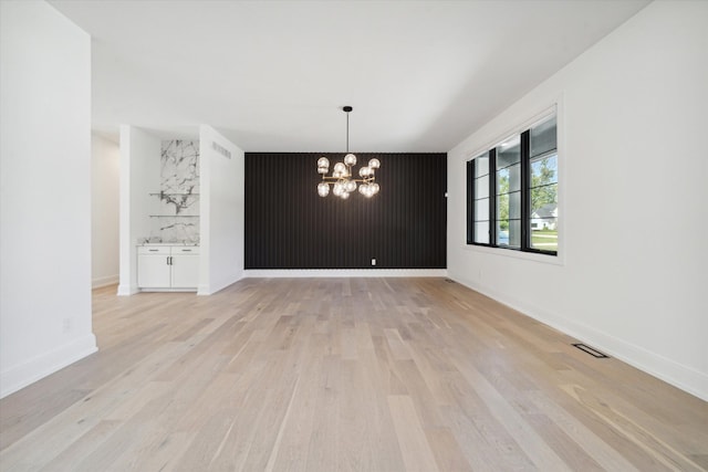 unfurnished dining area featuring a chandelier and light hardwood / wood-style floors