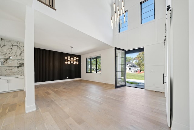 foyer entrance with a high ceiling, light hardwood / wood-style flooring, and a notable chandelier