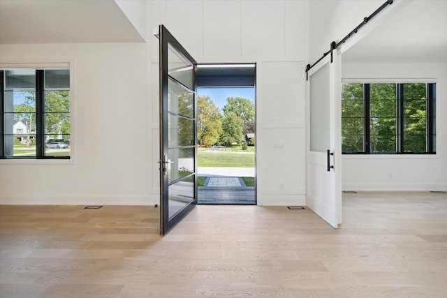 foyer with a barn door, light hardwood / wood-style flooring, and a healthy amount of sunlight