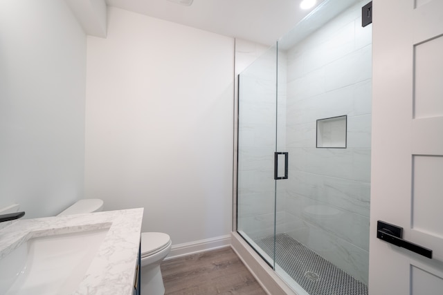 bathroom with hardwood / wood-style flooring, vanity, toilet, and walk in shower