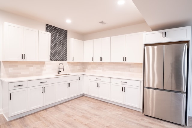 kitchen featuring stainless steel fridge, sink, white cabinets, and light hardwood / wood-style floors