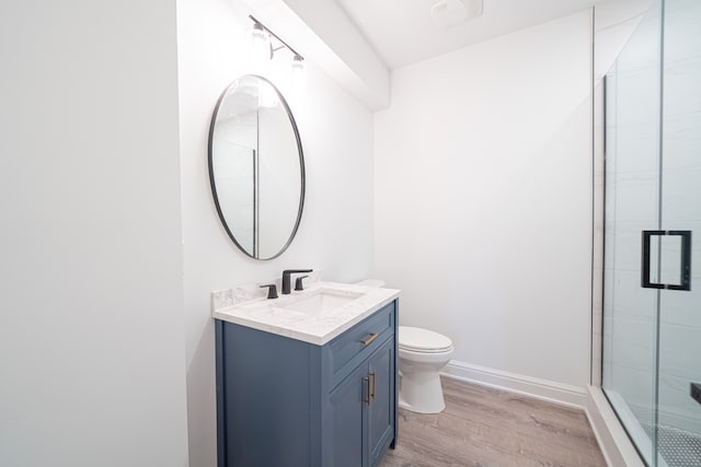 bathroom featuring hardwood / wood-style flooring, vanity, toilet, and a shower with door