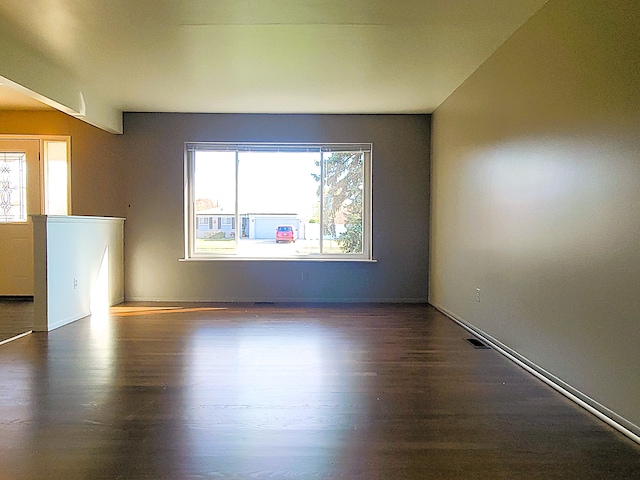 unfurnished room featuring dark hardwood / wood-style flooring and a healthy amount of sunlight