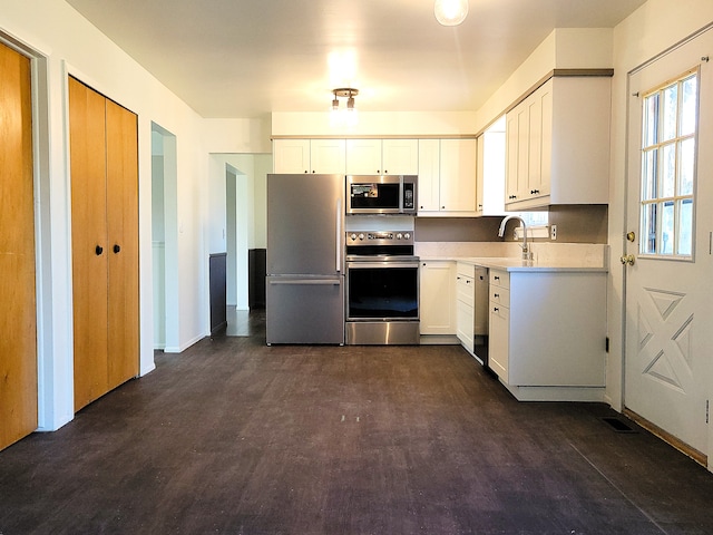 kitchen featuring appliances with stainless steel finishes, white cabinetry, and dark wood-type flooring