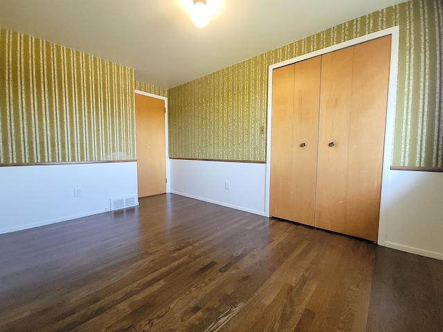 unfurnished bedroom with dark hardwood / wood-style flooring and a closet