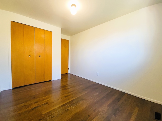 unfurnished bedroom featuring a closet and dark hardwood / wood-style floors