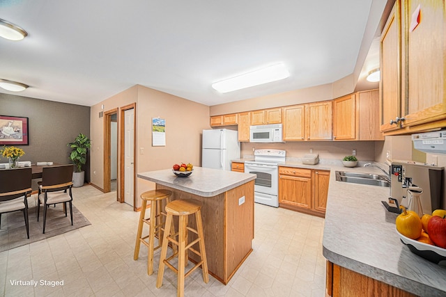 kitchen featuring white appliances, a kitchen island, a breakfast bar area, and sink