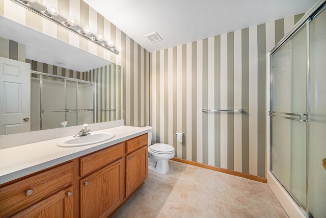 bathroom featuring a shower with door, vanity, and toilet