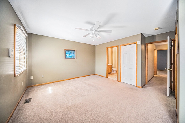 unfurnished bedroom featuring ceiling fan, ensuite bathroom, and light carpet