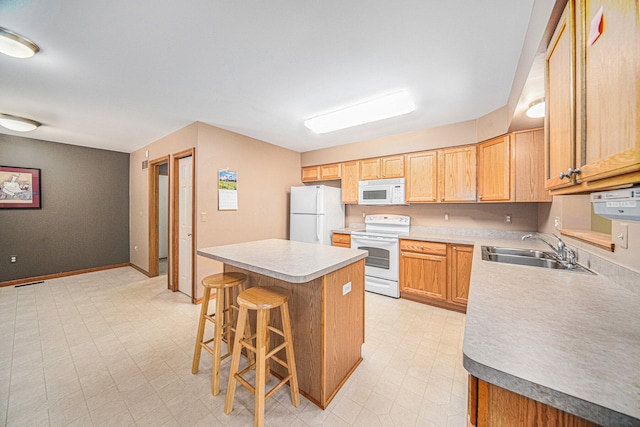 kitchen with a kitchen breakfast bar, white appliances, a center island, and sink