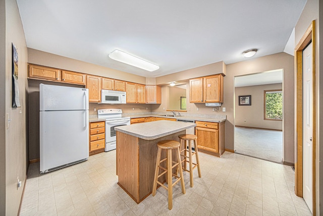 kitchen featuring a kitchen breakfast bar, white appliances, light colored carpet, sink, and a kitchen island