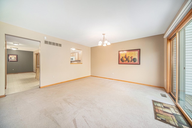 carpeted spare room featuring a notable chandelier