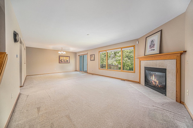 unfurnished living room with light carpet, a fireplace, and a notable chandelier