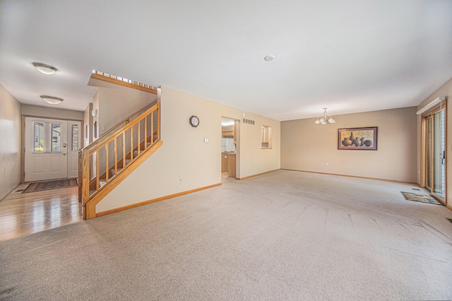 unfurnished living room featuring light carpet and an inviting chandelier