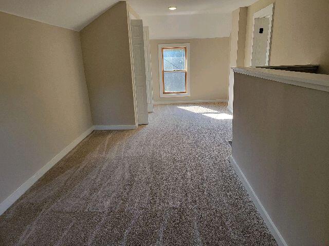 hallway featuring light carpet and lofted ceiling