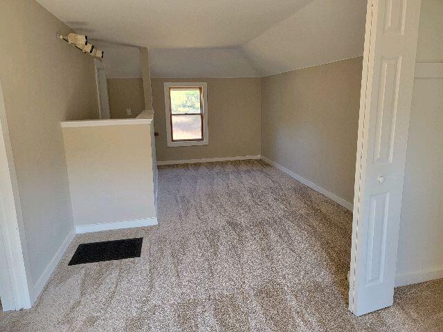 unfurnished room featuring lofted ceiling and light carpet