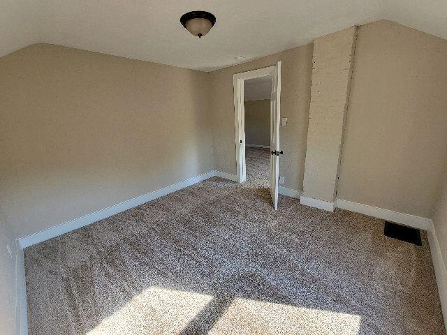 spare room with carpet and lofted ceiling