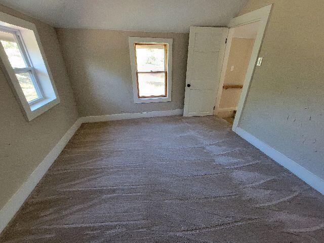 spare room with a textured ceiling, carpet floors, and vaulted ceiling