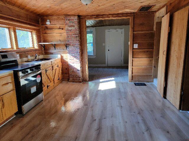 kitchen featuring range, light wood-type flooring, a healthy amount of sunlight, and wood ceiling