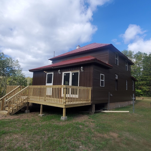 rear view of property featuring a lawn and a deck