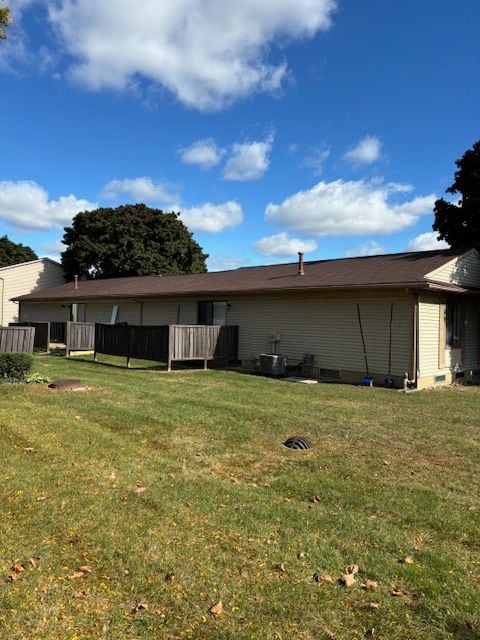 back of property featuring a lawn and central AC