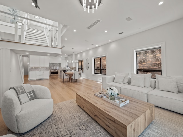 living room with light wood-type flooring, a fireplace, and a chandelier