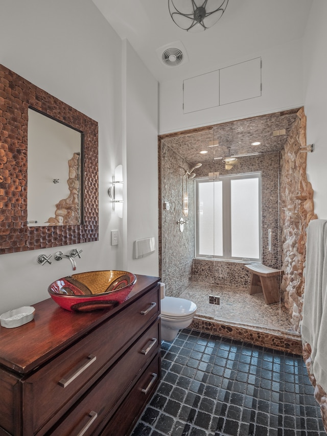 bathroom featuring vanity, toilet, and tiled shower