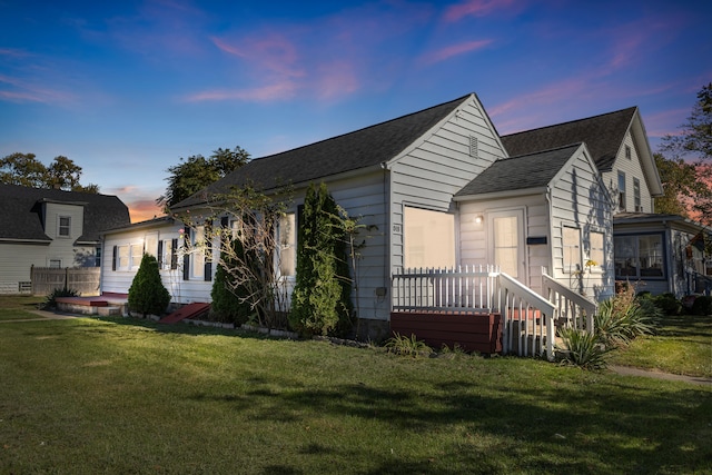 property exterior at dusk featuring a lawn