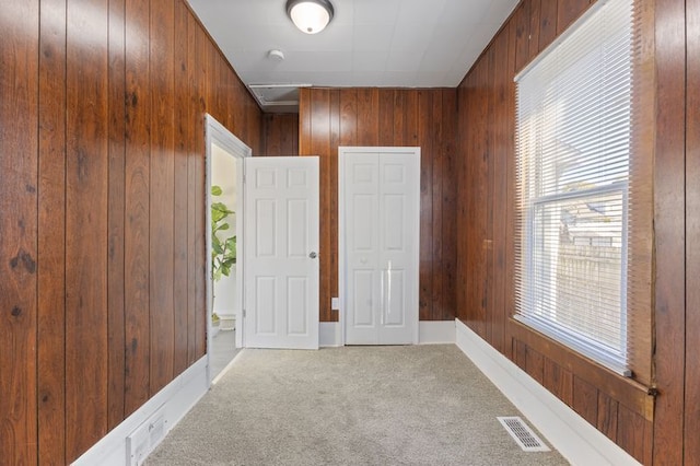 unfurnished bedroom featuring carpet and wooden walls