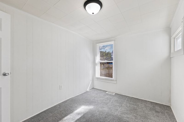 carpeted spare room with wooden walls