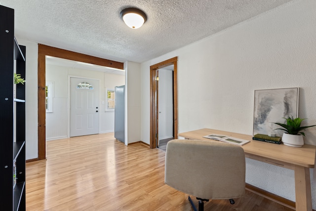 office with light hardwood / wood-style flooring and a textured ceiling