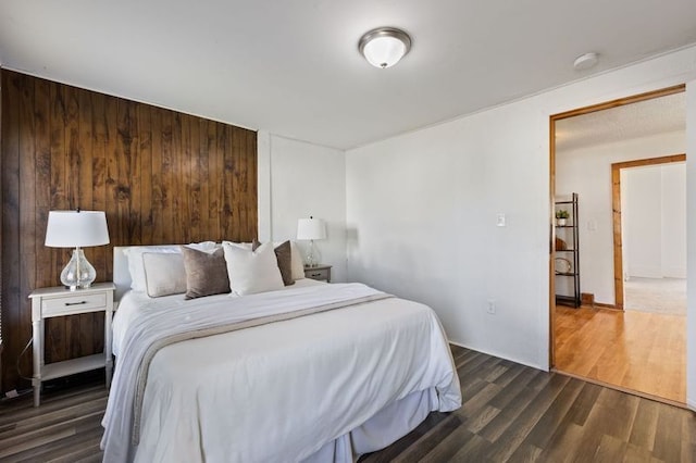 bedroom with dark hardwood / wood-style floors and wooden walls