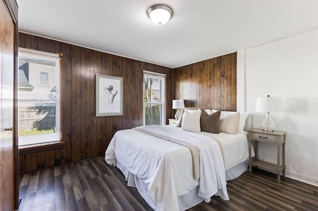 bedroom with dark hardwood / wood-style floors, multiple windows, and wood walls