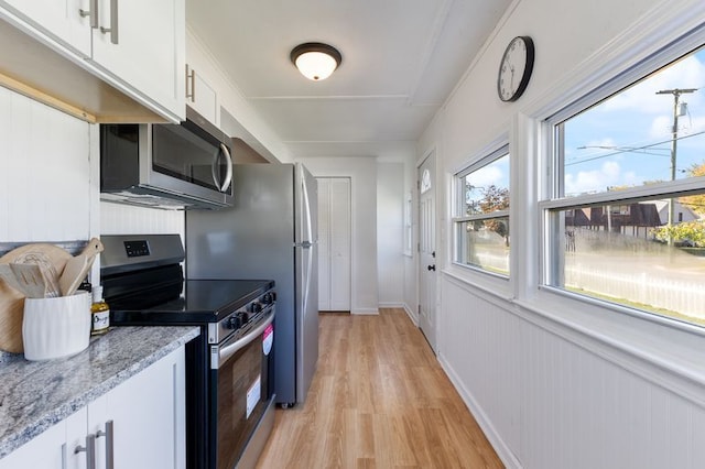 kitchen with light hardwood / wood-style floors, light stone countertops, white cabinetry, and stainless steel appliances