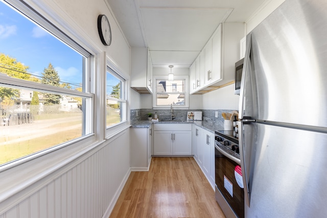 kitchen featuring light stone countertops, white cabinetry, sink, stainless steel appliances, and light hardwood / wood-style floors